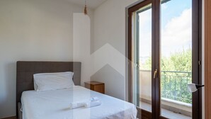Una camera da letto con un letto, un comodino, una finestra che offre una vista e una porta che dà su un balcone esterno.
