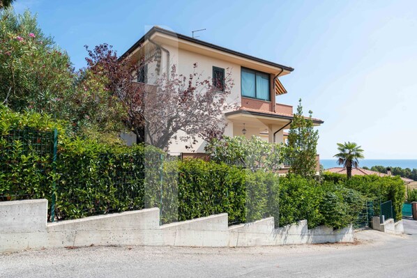 A two-story house with a balcony, surrounded by greenery and a clear sky. - Villa Mila with beautiful sea view (Pineto)