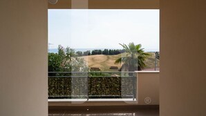 Un balcone con vista su un prato, una palma e una recinzione in lontananza.