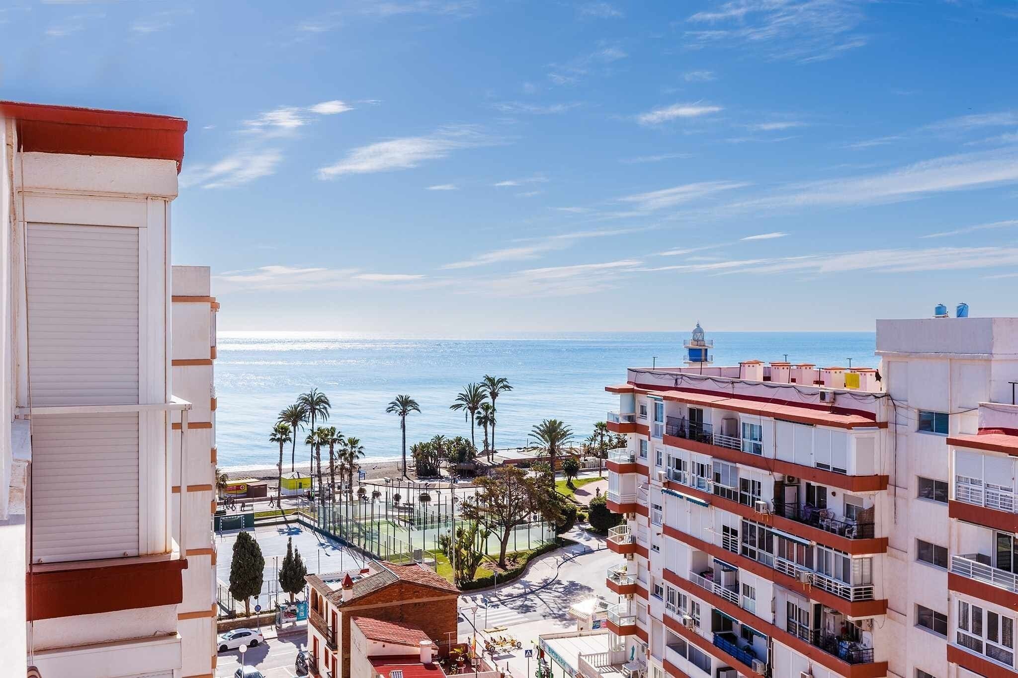A coastal residential area with buildings overlooking the sea, featuring balconies and a clear view of the ocean.