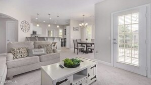 A spacious living room with a sofa, coffee table, and dining area. - Cozy condo in Litchfield Park (Litchfield Park)