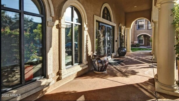 A covered walkway with arched windows and columns, leading to a building entrance. - Cozy condo in Litchfield Park (Litchfield Park)