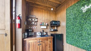 Une cuisine de taille réduite, avec des meubles en bois, un réfrigérateur noir, un four à micro-ondes et un extincteur.