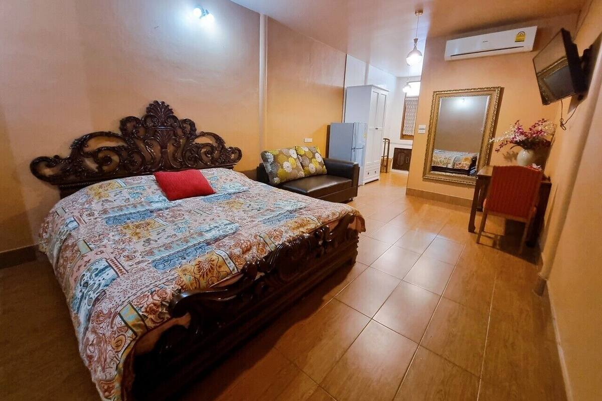 A bedroom with a large bed, a dresser, a mirror, and an air conditioning unit.