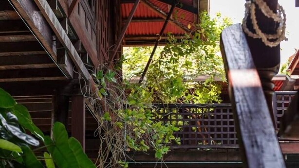 A wooden deck with a pool, stone pillars, and a statue. - Ruennakornin (Bang Kruai)
