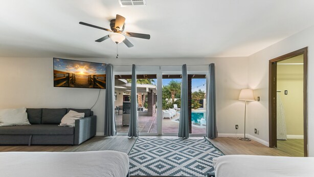 A hotel room with two beds, a ceiling fan, a large window with a view of a pool and outdoor area, and a painting on the wall. - Amazing 6 BRD, Pool, Theater, Billiard, Poker, and Games near the Strip (Las Vegas)
