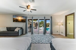 A hotel room with two beds, a ceiling fan, a large window with a view of a pool and outdoor area, and a painting on the wall. - Amazing 6 BRD, Pool, Theater, Billiard, Poker, and Games near the Strip (Las Vegas)