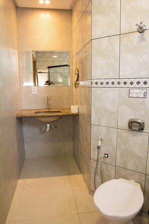 A small bathroom with a sink, toilet, and shower. - Fiori Suítes  (Goiânia)