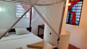 A bedroom with a bed, a bedside table, a nightstand, a window with a curtain, and a wall-mounted lamp. - 2 Bed House - Sleeps 4 - Pool - Garden - Parking (Diani Beach kenya)