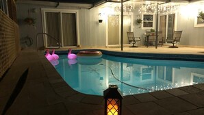 A swimming pool with pink flamingo floats, a lantern, and a covered patio area with chairs and a table. - Gorgeous Pool house 5 min from the beach, shopping and restaurants I (Venice)