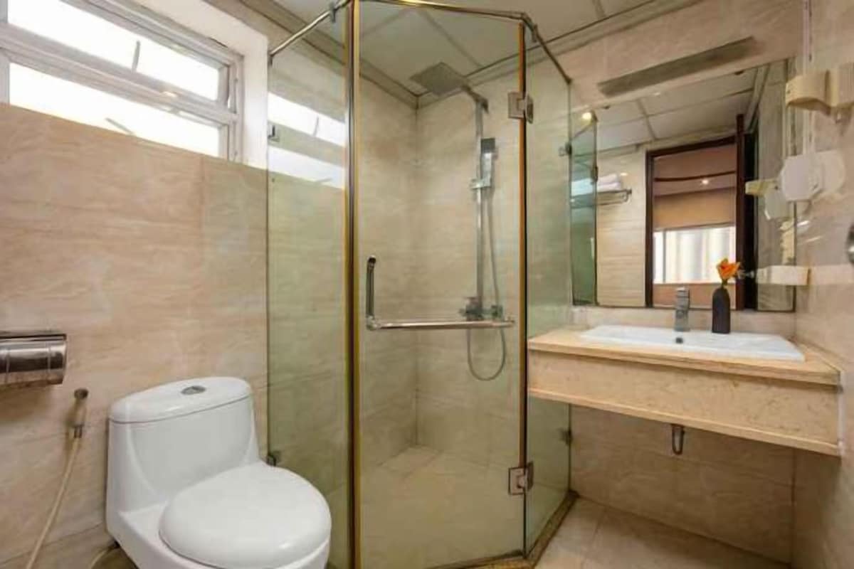 Een moderne badkamer met een douchecabine van glas, een wit toilet en een wastafel met spiegel.