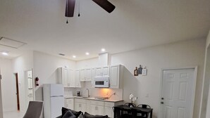 A living room with a dark brown sofa, a small wooden table, and a ceiling fan. - New and luxurious (Tampa)
