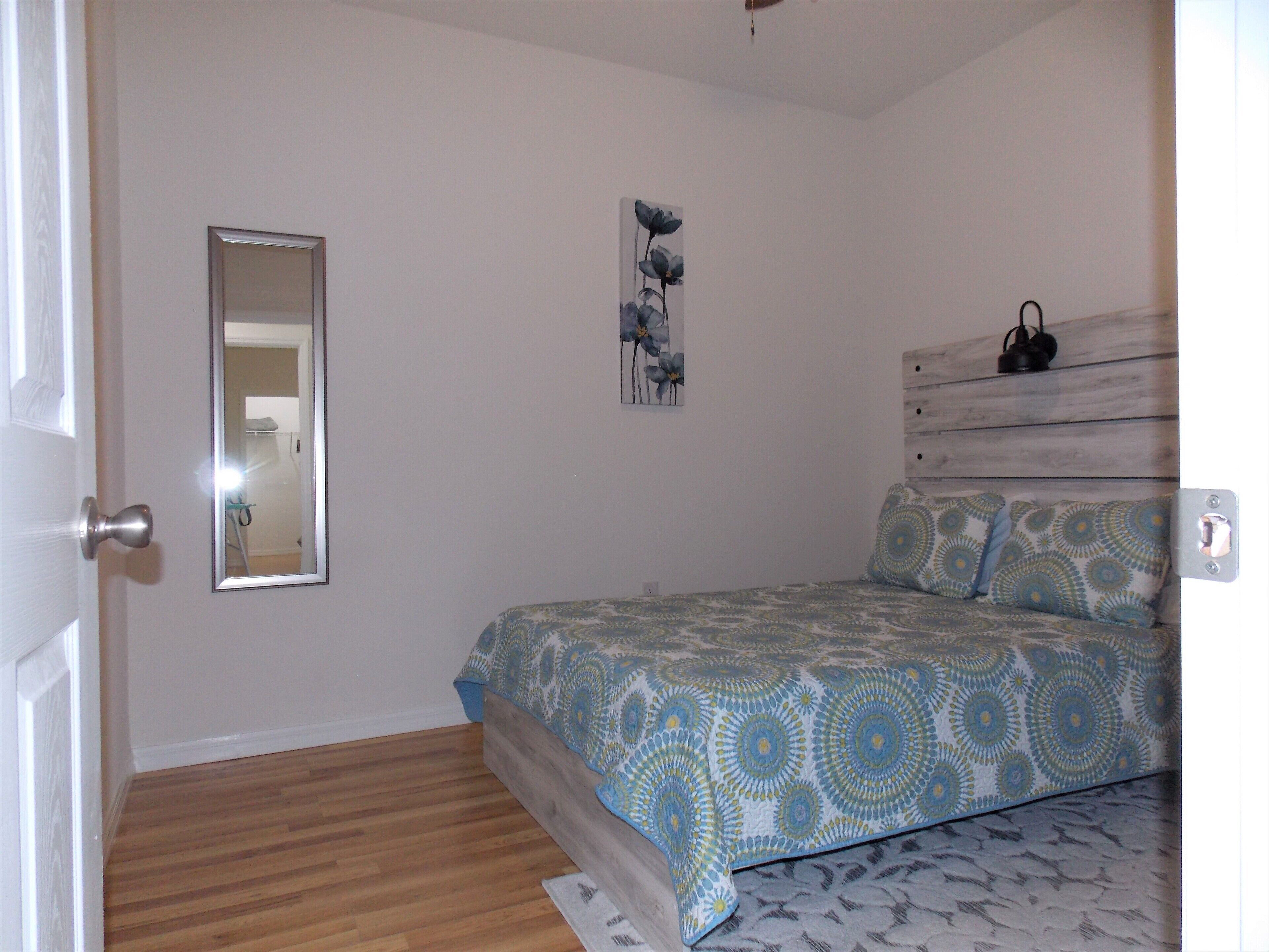 Ein Schlafzimmer mit einem Bett, einem Spiegel und einem Wandbild.