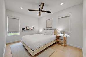 Une chambre à coucher avec un lit, une table de chevet et un ventilateur de plafond.