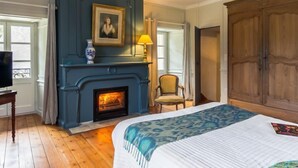 Een kamer met een open haard, een bed, een stoel, een televisie en een kledingkast.