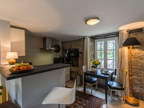 A compact kitchen with a central island, a dining area with a table and chairs, and a stone wall.