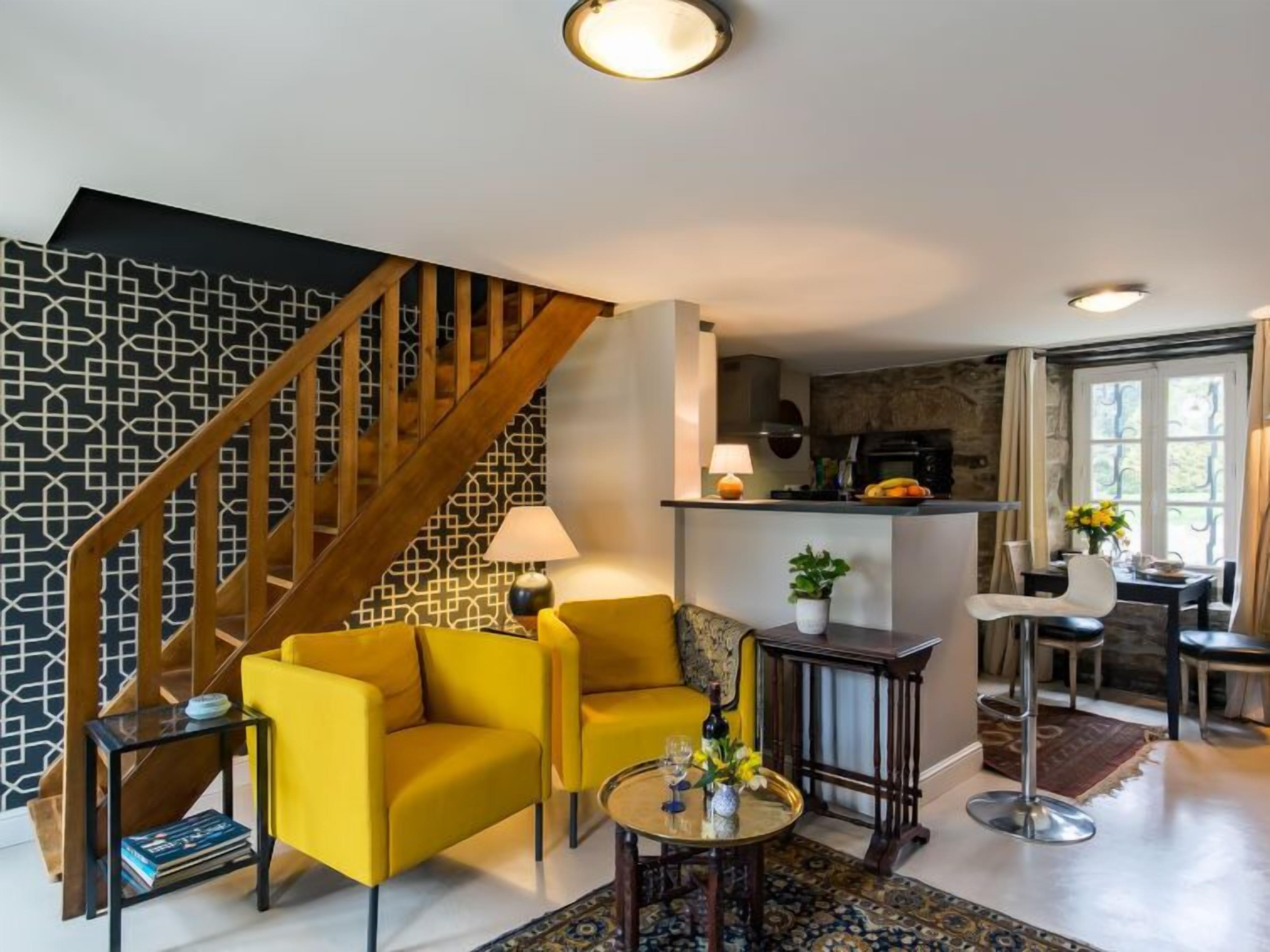 A modern living room with a staircase, a kitchen area, and a dining space.