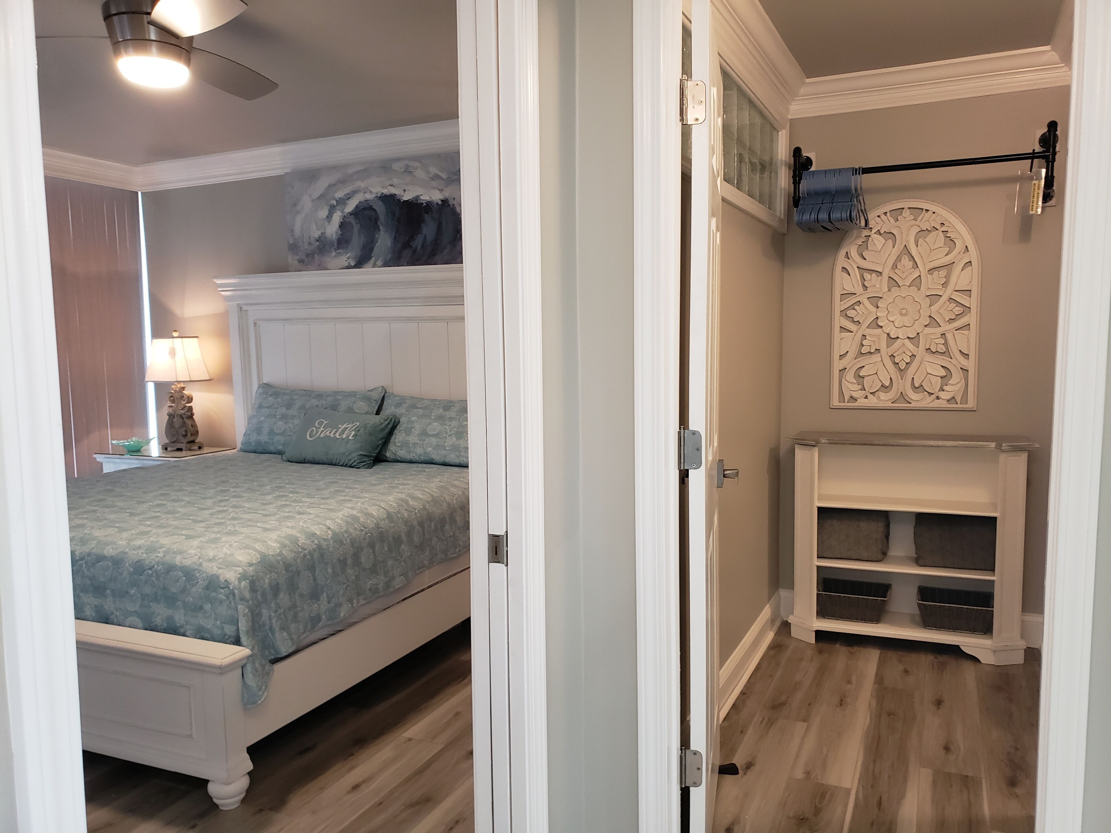 Une chambre à coucher comprenant un lit, une table de chevet, une lampe, un mur orné d’un panneau décoratif et une étagère intégrée.
