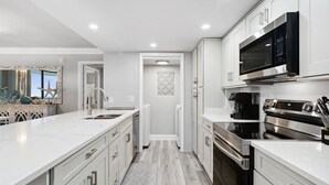 A modern kitchen with white cabinetry, stainless steel appliances, and a central island.