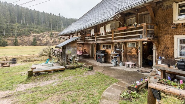 Un edificio rústico de madera con balcón, mobiliario exterior y zona de barbacoa.