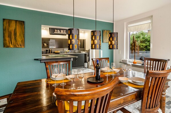 A dining area with a wooden table, chairs, and hanging pendant lights.