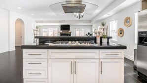 A modern kitchen with a central island, stainless steel appliances, and white cabinetry.