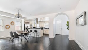 A spacious kitchen with dark flooring, white cabinetry, and a dining area with a table and chairs.