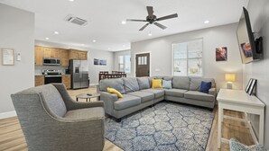 A modern living room with a gray sectional sofa, a gray armchair, and a patterned rug. - Heart of Kanab Home (Kanab)