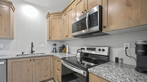 A modern kitchen with wooden cabinets, granite countertops, stainless steel appliances including a microwave, stove, and dishwasher, and a built-in oven. - Heart of Kanab Home (Kanab)