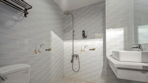Uma casa de banho moderna com sanita, chuveiro com cabeça de duche manual, lavatório e espelho.