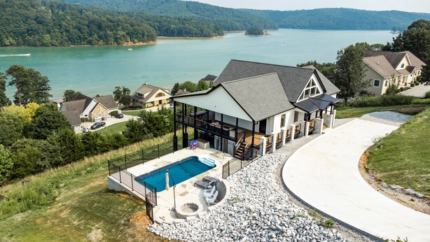 Una casa grande con piscina, un patio cubierto y vistas a un lago.