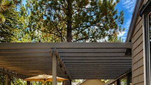 Un patio couvert avec des meubles d’extérieur, un barbecue et une vue sur une maison.