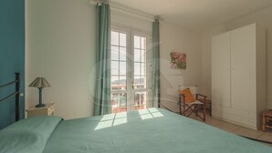 A bedroom with a bed, a chair, a wardrobe, and a window with curtains.