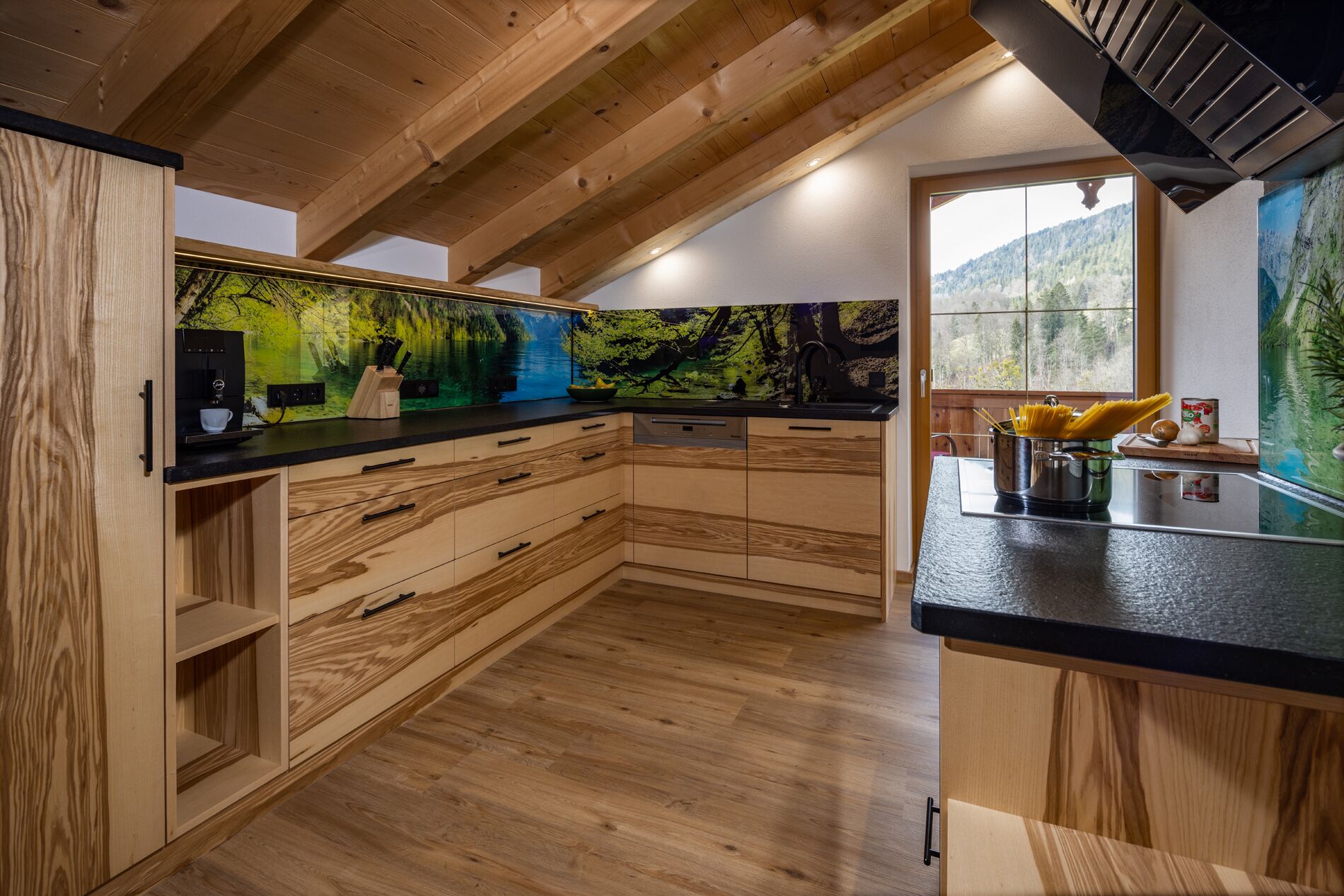 A modern kitchen with wooden cabinetry and a large window offering a view of the outdoors.