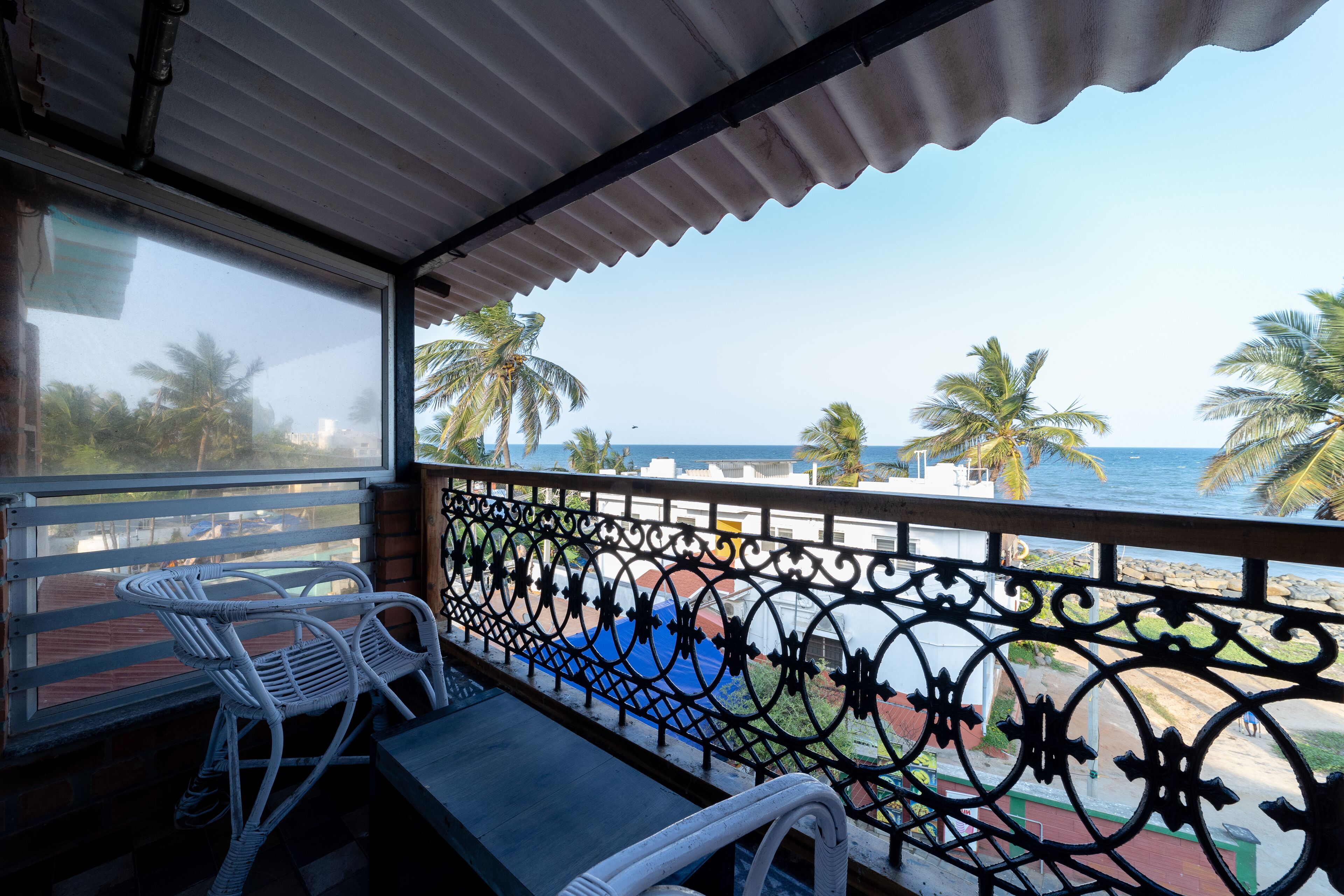 Ein Balkon mit Blick auf das Meer, Palmen und einem Metallgeländer.