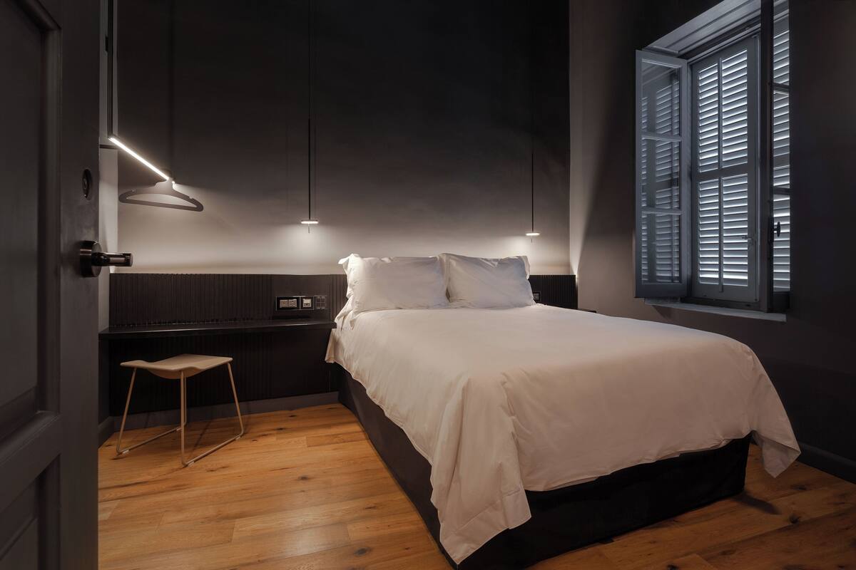 Ein Schlafzimmer mit einem Bett, einem Nachttisch und einem Fenster mit Jalousien.