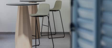 Una habitación moderna con una mesa redonda y dos sillas, una puerta con manija y piso de baldosas.
