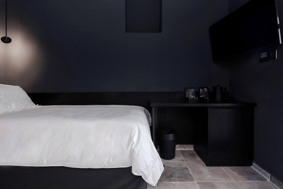 Ein modernes Hotelzimmer mit Bett, Schreibtisch und Fernseher.