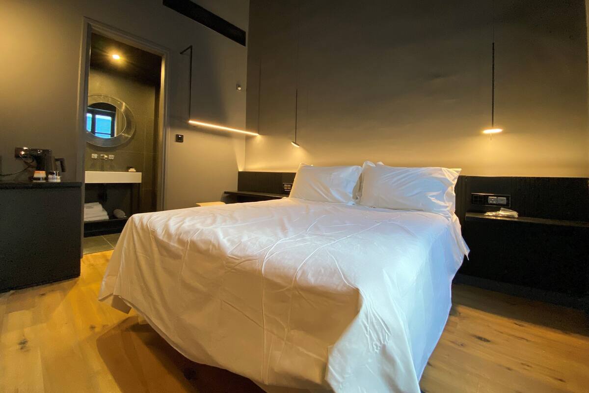 Ein Hotelzimmer mit Bett, Nachttisch, Spiegel und Holzboden.