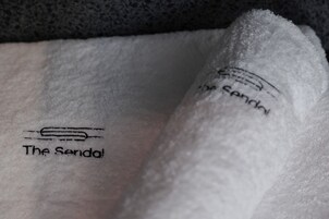 A close-up of a white towel with the text "The Sandal" and a logo.