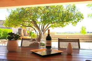 Une table en bois avec une bouteille de vin, deux verres à vin et un petit vase.