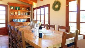 Ein Essbereich mit einem Holztisch, Stühlen, einer Chandelier und einem Bücherregal mit Büchern und Dekoration.