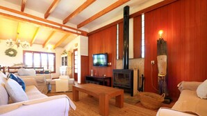 Ein gemütliches Wohnzimmer mit Holzbalken, einem Kamin und einem Fernseher.