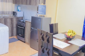 A kitchen with a microwave, stove, refrigerator, and a chalkboard sign.