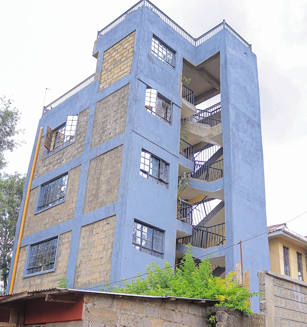 A multi-story building with a blue facade, multiple balconies, and visible windows.