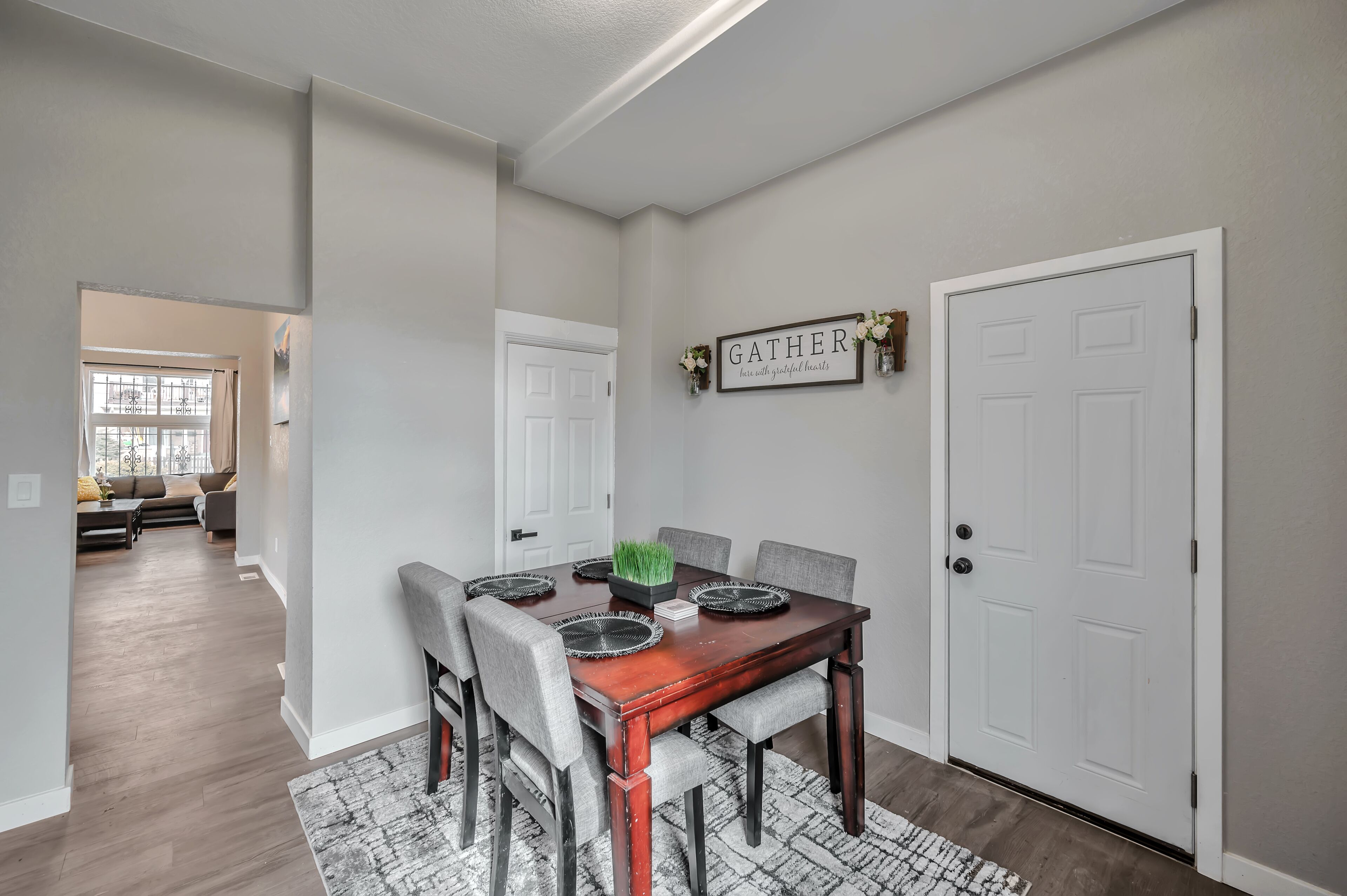 A dining area with a wooden table, grey upholstered chairs, and a rug.