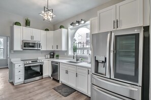 Eine moderne Küche mit weißen Schränken, Edelstahlgeräten, einem Backofen und einem Kühlschrank.