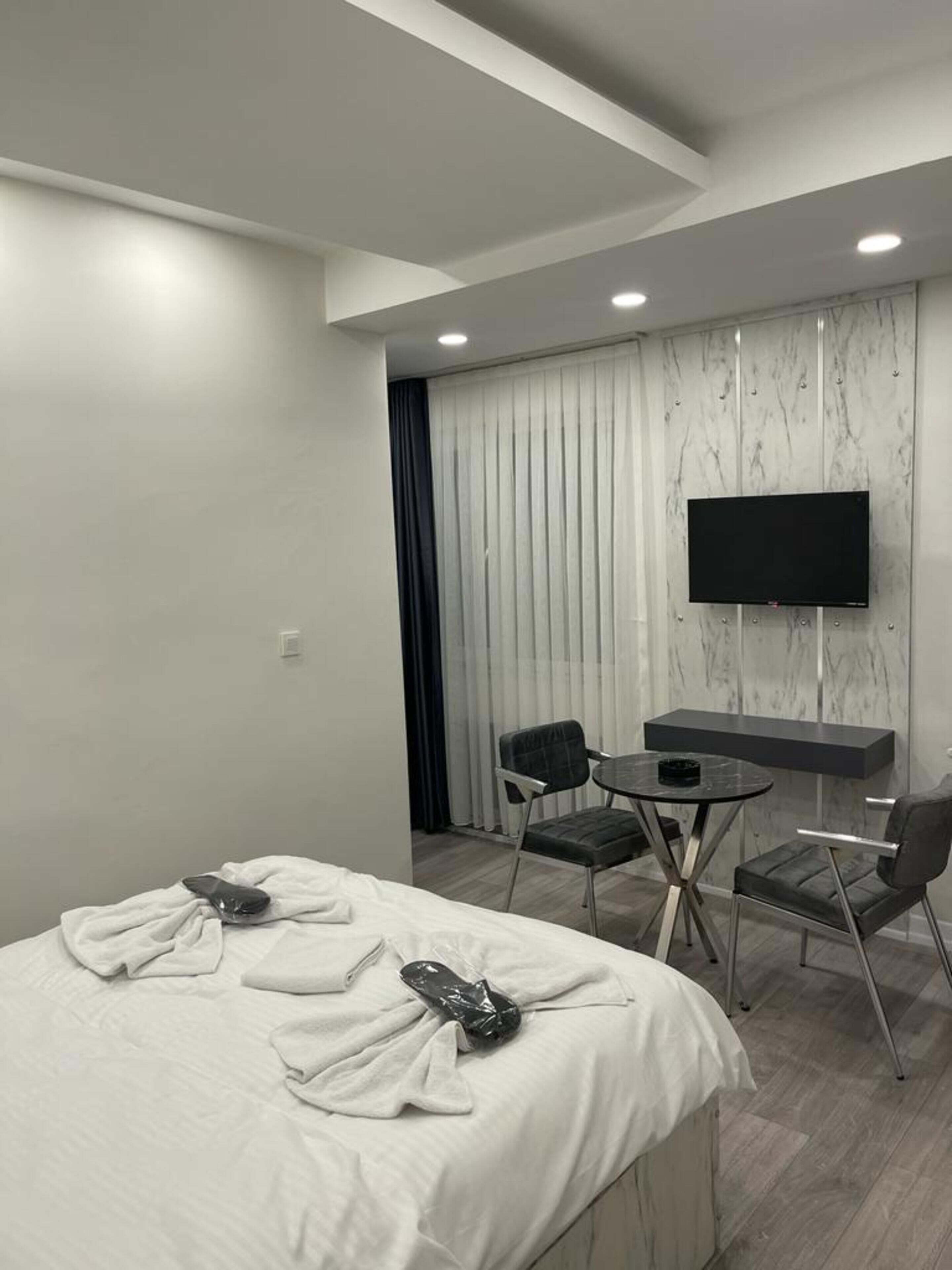 Ein modernes Hotelzimmer mit einem Bett, einem Schreibtisch, zwei Sesseln und einem Fernseher.