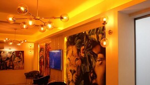 Una habitació amb un llum modern, un quadre abstracte gran i una televisió penjada a la paret.