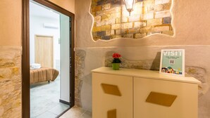 Un hall d’accueil d’hôtel avec un mur en pierre, un lit en arrière-plan et un panneau sur le comptoir.